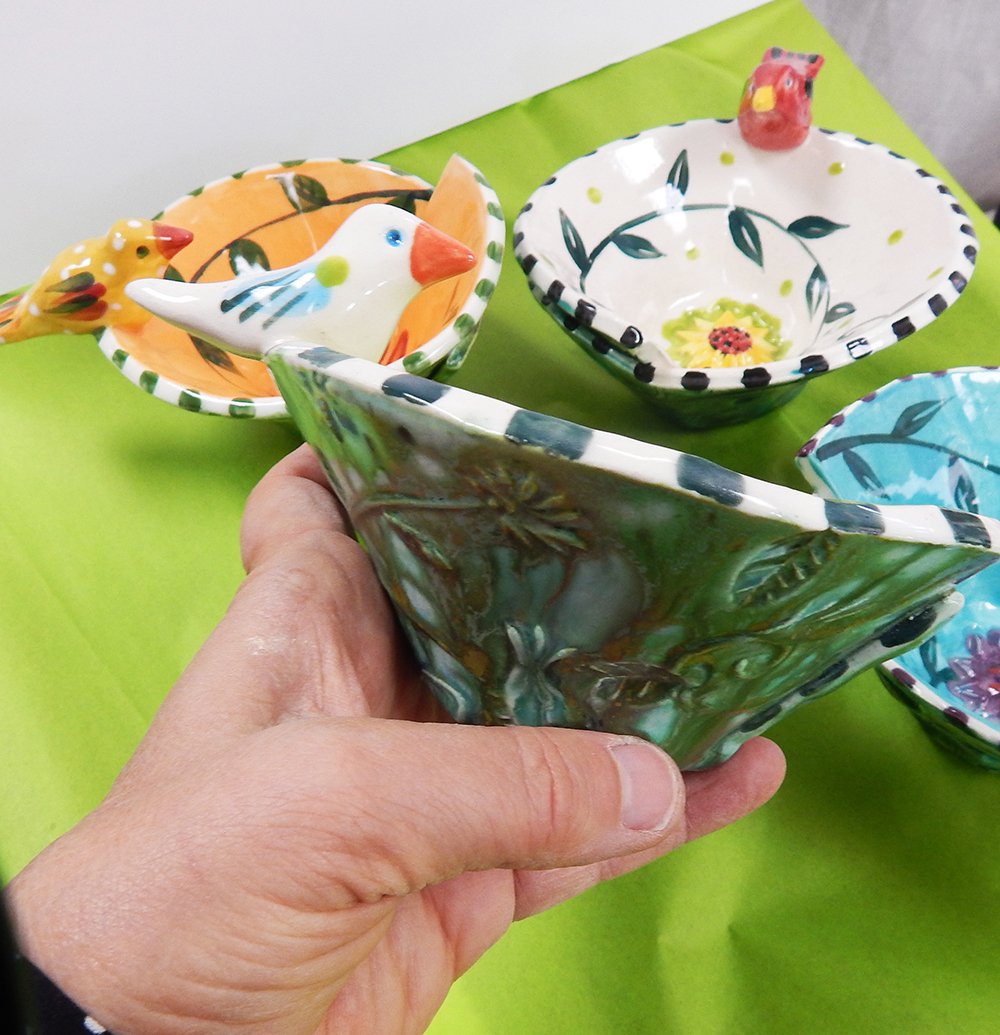 the side view of the handmade ceramic bird bowl with the flow glaze defining a garden pattern