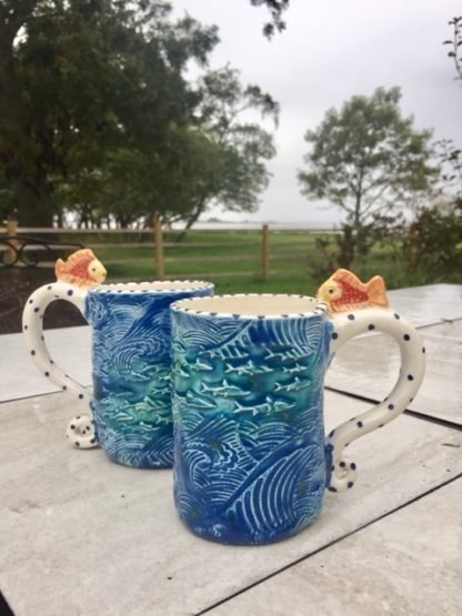 mugs with big tsunami waves and fish all over them